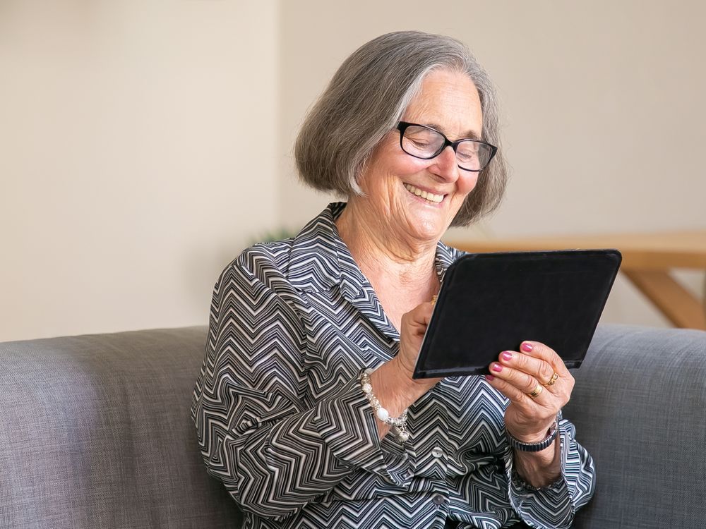 Mulher de cabelos grisalhos sorrindo com o tablet